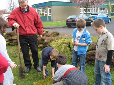 Building a Mesolithic hut. St Malachy�s pupils cut turf sods for the walls.