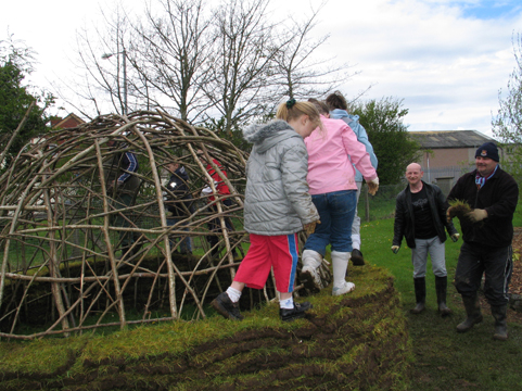 Building a Mesolithic hut. St Malachy's pupils start to build up the walls.